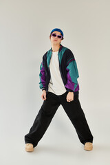 A confident young man displays a trendy bomber jacket and casual style in a vibrant studio.