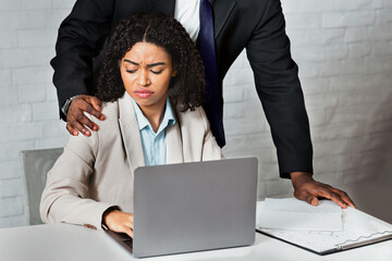 Sexual harassment in office concept. African American boss molesting his female employee at...