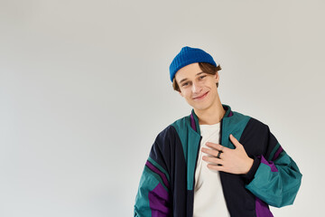 A handsome young man stands confidently, dressed in a colorful bomber jacket, in a studio.