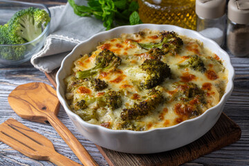 Casserole Cauliflower and broccoli baked with cheese sauce in a pot close-up on a wooden table. Horizontal top view from above. Broccoli gratin.