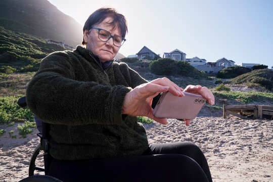 Woman in wheelchair taking selfie outdoors