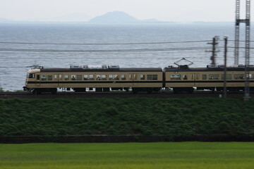 一面の田園地帯と琵琶湖を背景に疾走する117系電車_2010/8/25撮影