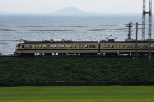 一面の田園地帯と琵琶湖を背景に疾走する117系電車_2010/8/25撮影