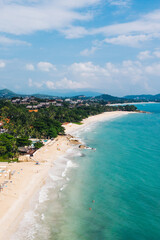 Aerial scenery view of white sand shore with turquoise clear sea water. Bird's eye panoramic view of picturesque lagoon with hotels on beach. Populated island in Thailand