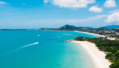 Aerial scenery view of white sand shore with turquoise clear sea water. Bird's eye panoramic view of picturesque lagoon with hotels on beach. Populated island in Thailand. Water Sport Activity