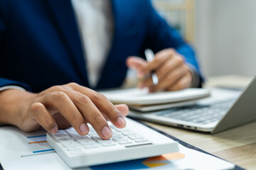 Business finance and budget management, Businessman using calculator and analyzing invoices and tax documents to manage company finances, Budget, Monthly expenses on desk with documents and reports.