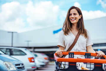 Smiling Woman Shopping Outdoors With a Cart in a Parking Lot