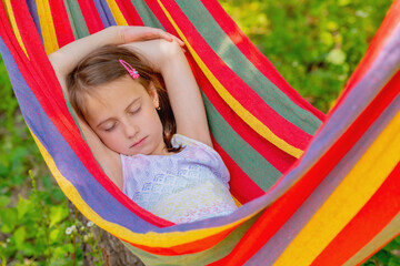 Portrait of young beautiful girl resting in comfortable hammock at green garden. Horizontal image.