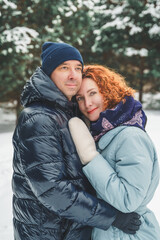 Love romantic love story. Happy couple of middle aged millennials, bright red-haired woman in winter snow park. Romantic date, kissing, hugging. Walking, having fun. Stylish blue clothes, jacket, hat