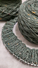 Fototapeta premium Knitted product from dark threads. Knitting a neck for a sweater with knitting needles.