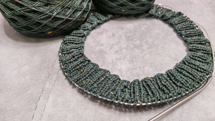 Knitted product from dark threads. Knitting a neck for a sweater with knitting needles.