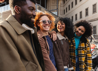 Happy multi ethnic friends laughing and walking together in the city