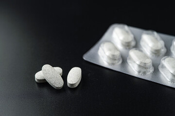white Pills Medicine tablet capsules in blister pack on a black background