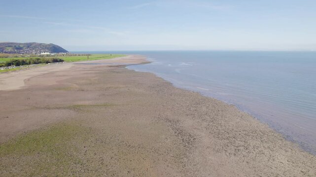 Drone flying over Dunster Beach with calm sea waters, on a sunny autumn day in Somerset, UK