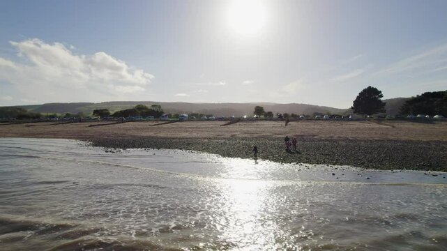 Drone flying on Dunster Beach during a sunny autumn day with calm waves and blue sky in Somerset, UK