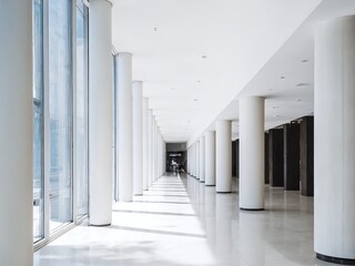 Obraz premium Spacious corridor with white columns and large windows in a modern building during the daytime