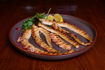 Grilled octopus with lemon on plate