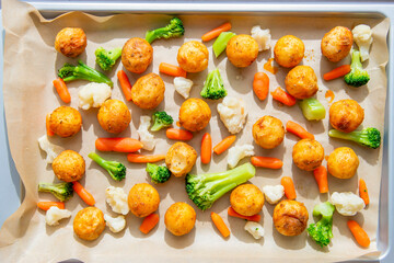 potatoes with vegetables baked on a baking sheet in the oven