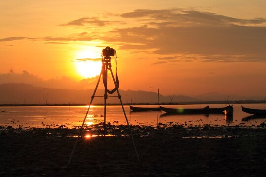 camera tripod on the lake with sunset background