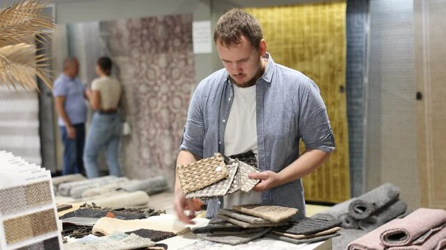 Man chooses the softest and most beautiful carpet from samples in a hardware store. High quality 4k footage
