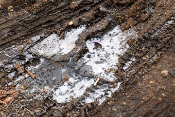 A detailed closeup view of a tire track along a dirt road surface