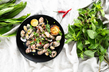 Clams and mussels with garlic and herbs served on a black plate with greens.
