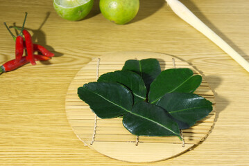 Thai herbal kaffir lime leaves placed on woven bamboo at a wooden table
