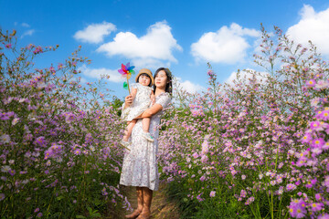 Cute mother and little daughter in a flower field,Happy mother with little daughter on lavender background. Beautiful woman and cute baby playing in meadow field. Family holiday in summer day.