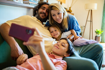 Happy family taking a selfie together while relaxing on the couch at home