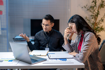 Stressed businesswoman feeling tired while working with colleague in office at night