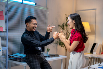 Two young business people having fun while working late in modern office at night