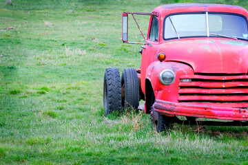 Obraz premium Old Junked Red Work Truck Abandoned in Green Field