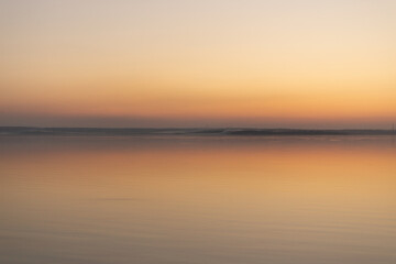 Obraz premium a sunset with a sunset in the background and a beach scene with a beach and trees.