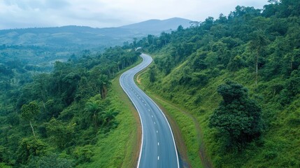 Fototapeta premium Curved scenic highway winding through lush green forested mountains under a cloudy sky