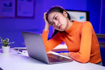 A woman is sitting at a desk with a laptop in front of her