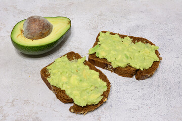 avocado toasts on a table with a half of avocado fruit