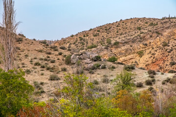 Hills and cliffs under a clear blue sky. A sad landscape with sparse grasses and trees. Konya; Turkey.