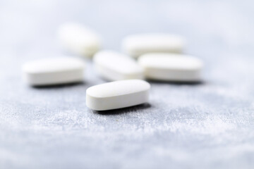 Arginine alpha-ketoglutarate (AAKG) tablets. Bodybuilding food supplements on wooden background. Soft focus. Close up. Copy space.