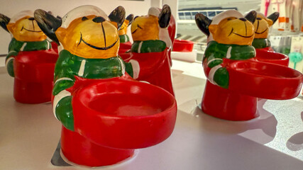 Festive Christmas reindeer-themed candle holders in bright red and green colors, symbolizing holiday decoration and celebration