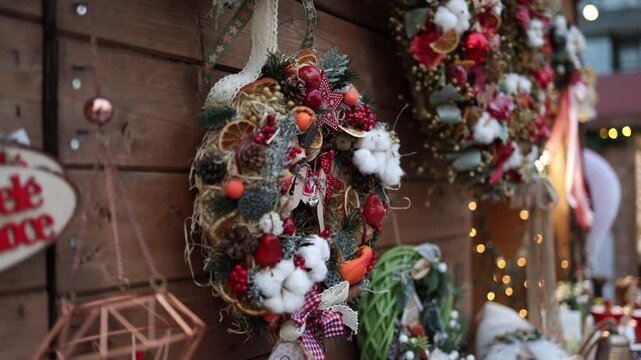 A close-up of a festive handmade Christmas wreath decorated with dried oranges, pinecones, cotton, red berries, and ribbons. The rustic design brings warmth and natural charm to the holiday season.