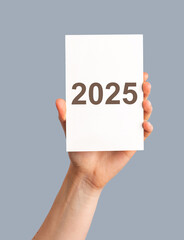 2025 new year, text numbers on paper postcard in hands.