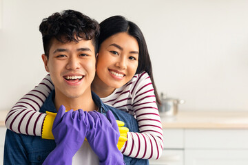Portrait of beautiful young asian couple house-keeping together, wearing rubber gloves, happy...