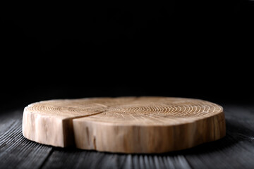 Round wooden plate with crack carved from tree trunk on black background. Can be used like stand for your object