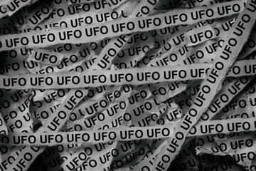 Strips of newspaper with the abbreviation UFO typed on them. Unidentified flying object. Black and...