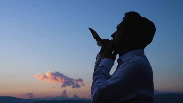 Jewish man blows shofar at sunset to celebrate the start of the Hebrew year