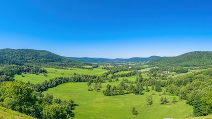Obraz premium Scenic Panoramic View of Lush Green Valley Under Clear Blue Sky
