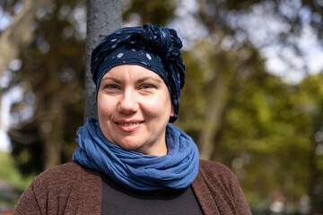 Close-up of a woman undergoing cancer treatment with her head covered with a scarf. Positive attitude