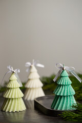 Three Christmas candles in the shape of Christmas trees with bows and small bells on a black plaster stand, copy space