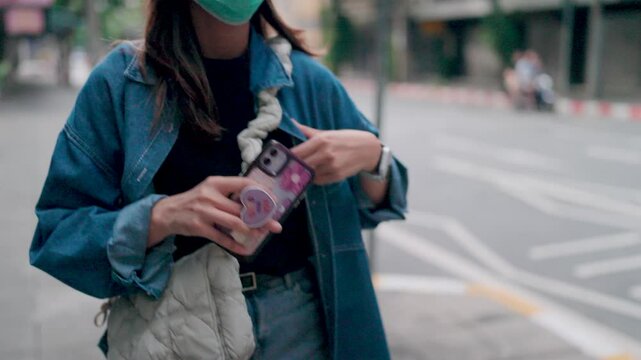 A young woman in a denim jacket and jeans confidently checks her phone, showcasing a unique and stylish phone case. This photo exudes a modern, urban vibe.  