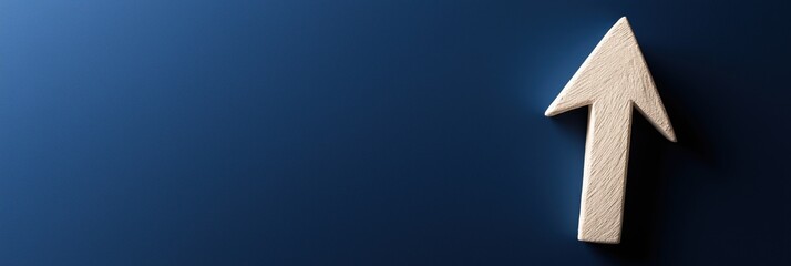 A simple, pointed wooden arrow placed on a plain blue surface, representing direction or progress.
